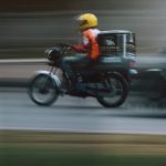 Fast-moving motorbike with rider in helmet zooming down a street in Abuja, Nigeria.